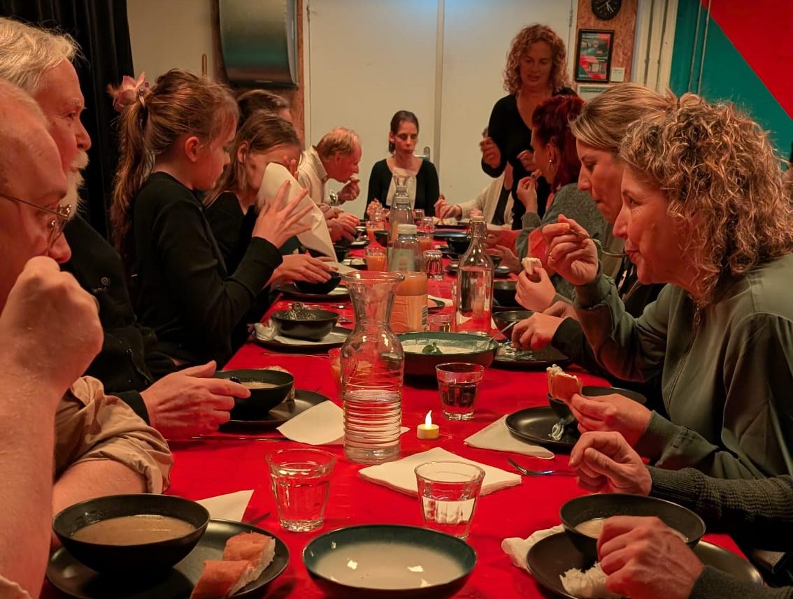 Groep mensen aan tafel eten soep
