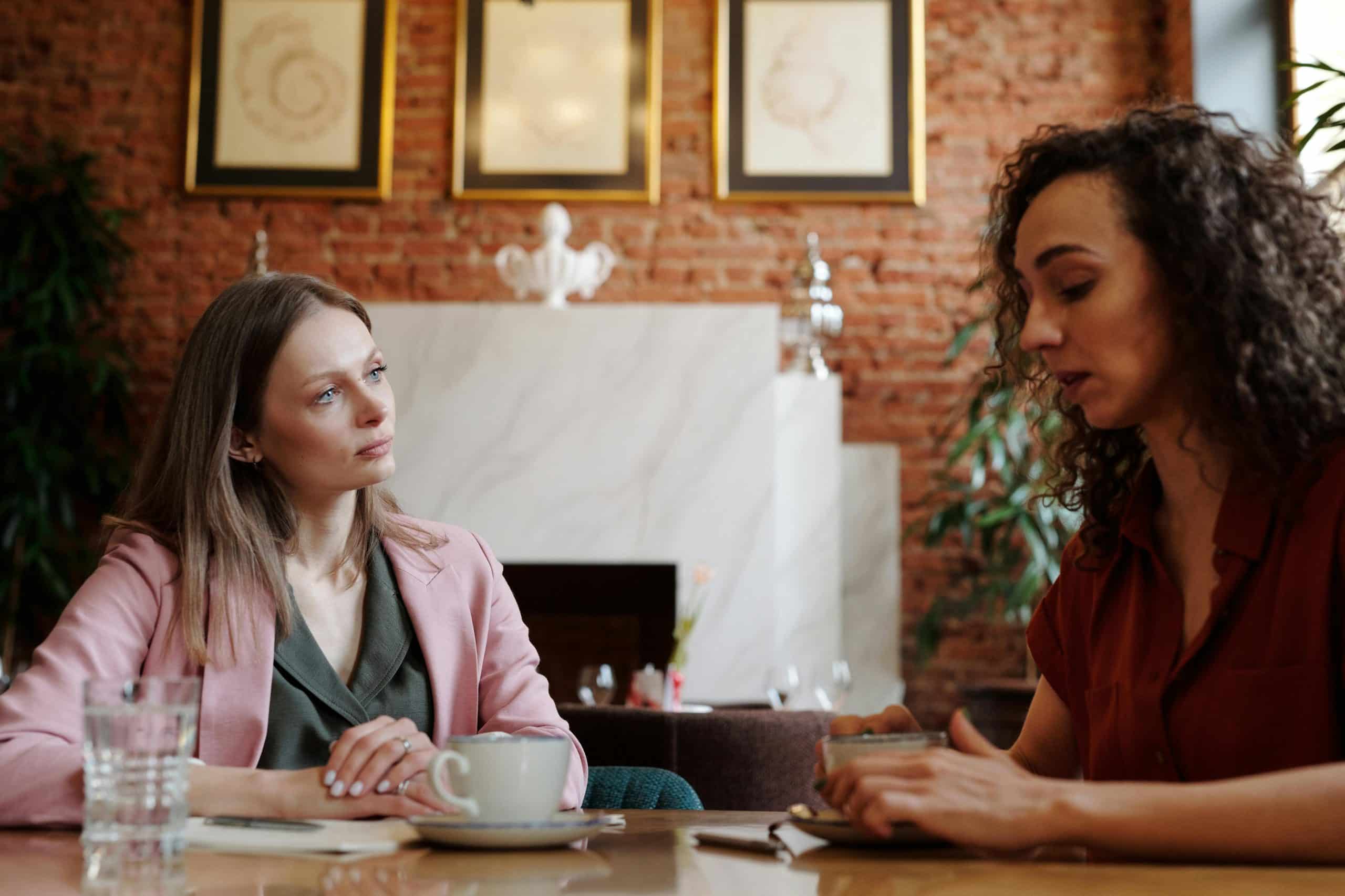 Twee vrouwen zitten aan tafel en hebben een serieus gesprek